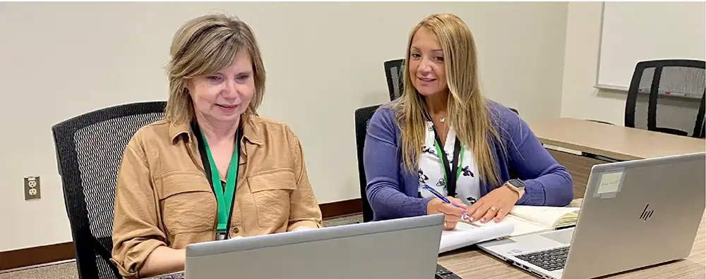 Two members of the RCDHU team working together in front of laptops