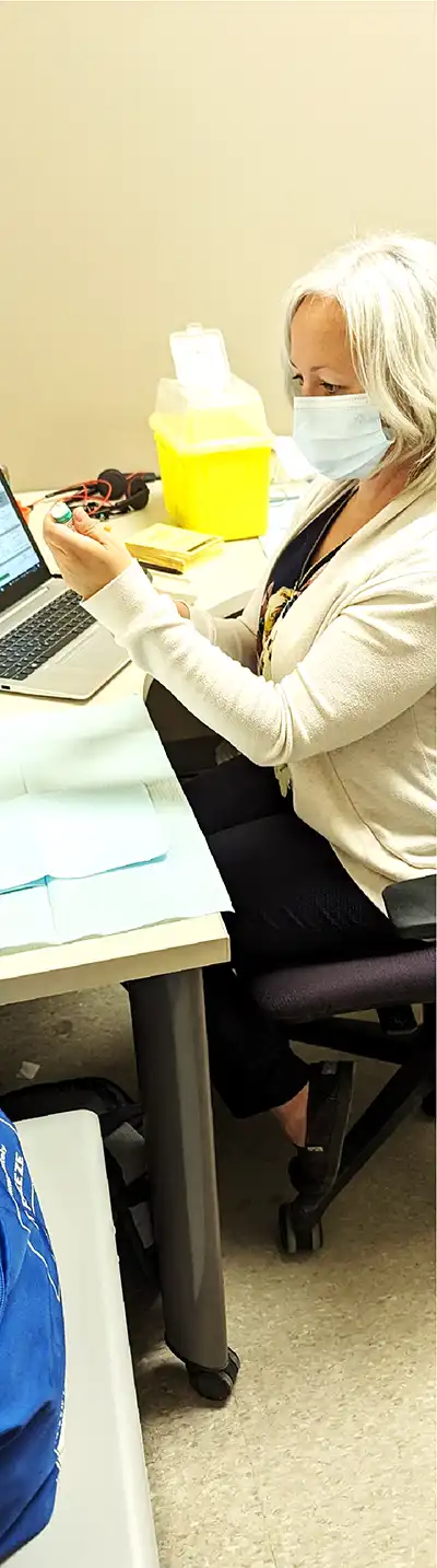 RCDHU nurse at their desk examining a vaccine vial